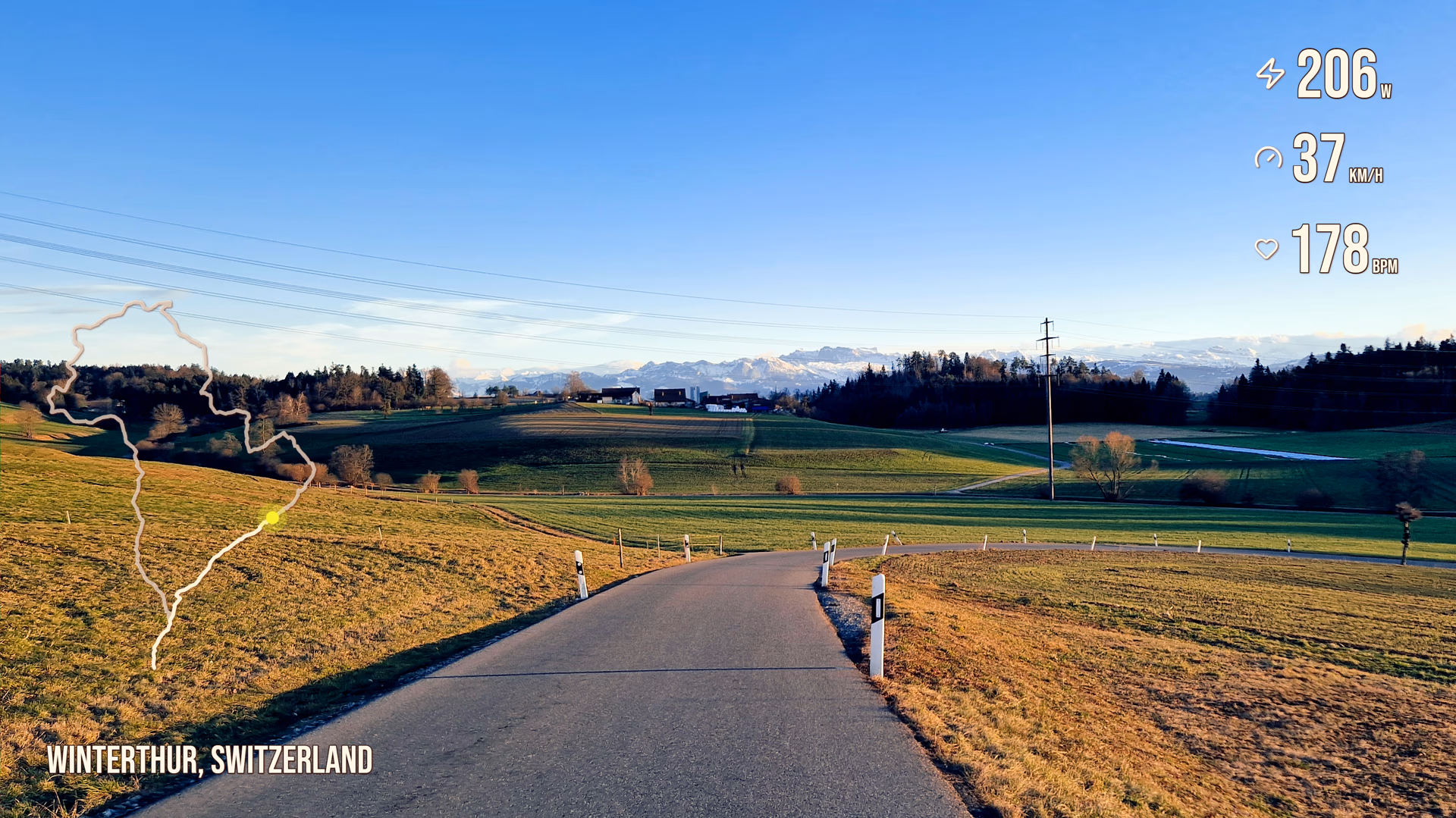 Swiss countryside road footage with route, power, speed, heart rate, and location label widgets.