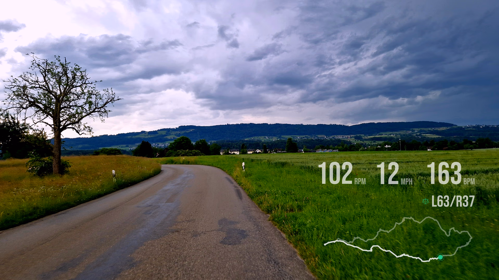 Stormy countryside road footage with cadence, speed, heart rate, balance, and route widgets.