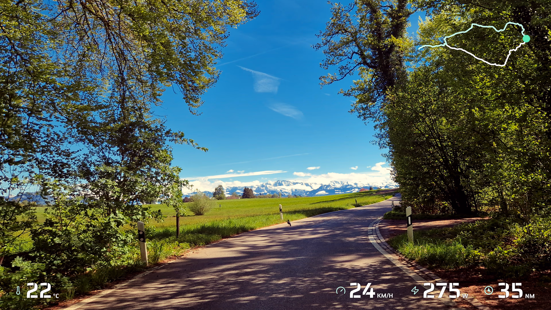 Countryside road footage with route, temperature, speed, power, and distance widgets.