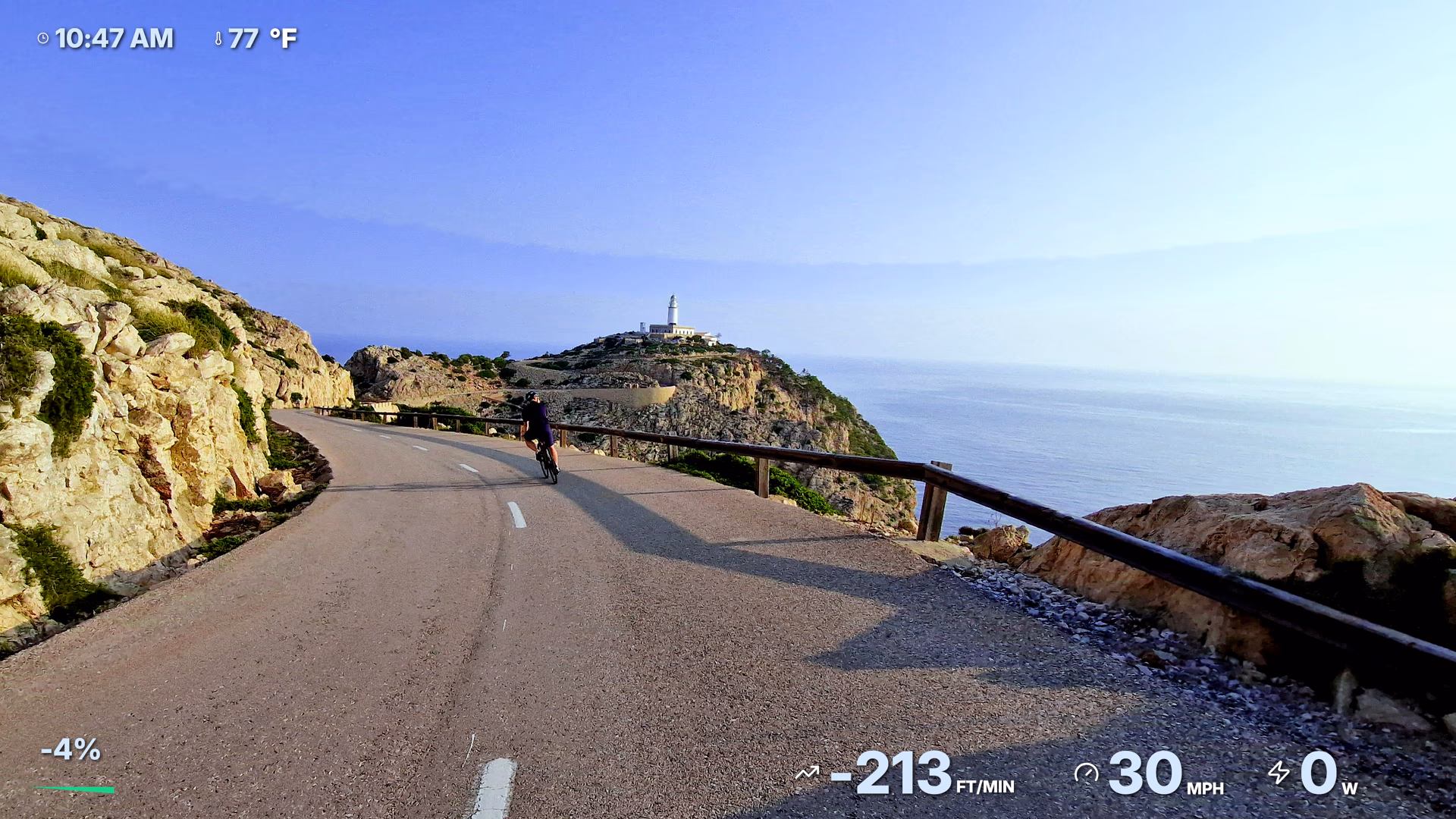 Coastal cycling footage with time, temperature, gradient, vertical speed, speed, and power widgets.
